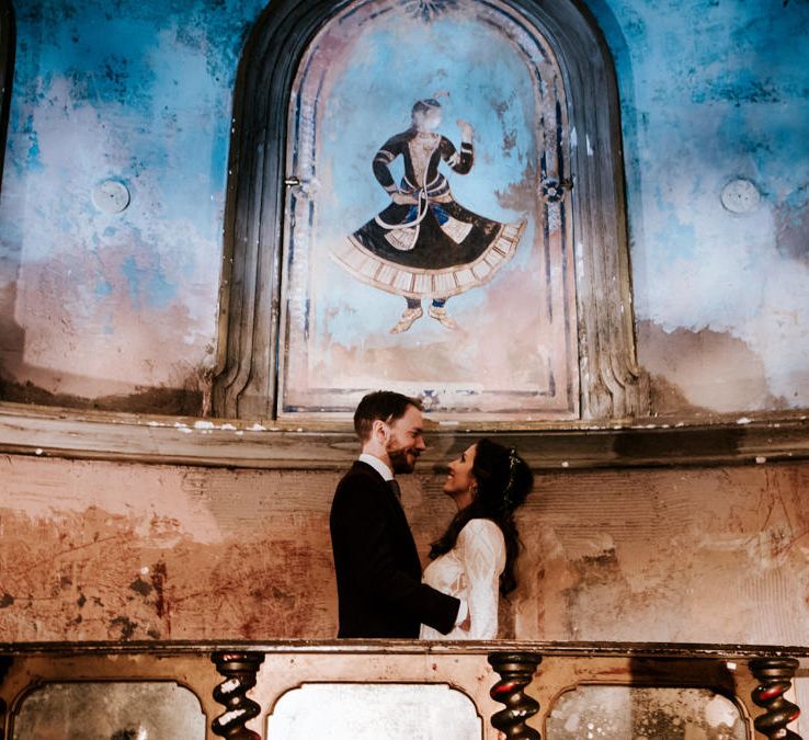 Bride in Grace Loves Lace Wedding Dress and Groom in Dark Suit Posing in Wilton's Music Hall