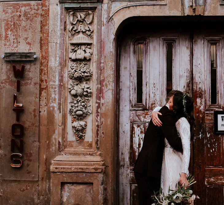 Bride in Grace Loves Lace Wedding Dress and Groom in Dark Suit Embracing