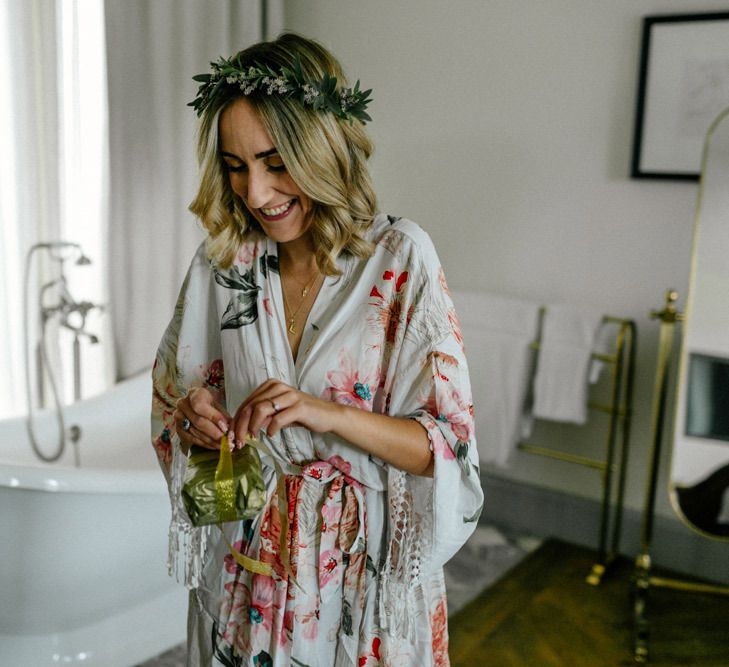 Bride on wedding morning in floral getting ready robe and flower crown