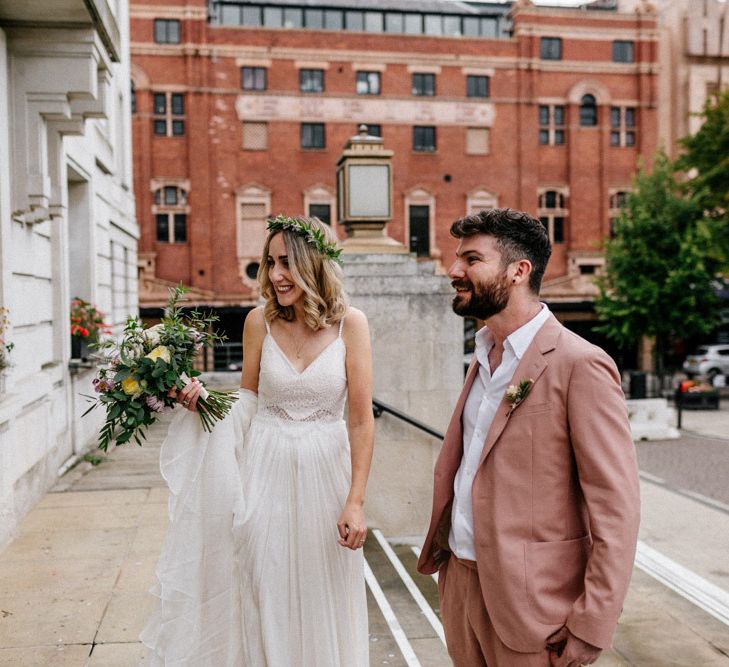 Stylish boho bride and groom in pink suit outside Hackney Town Hall