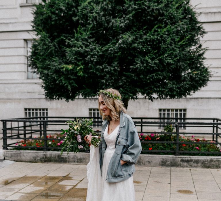 Stylish bride in Catherine Deane wedding dress, flower crown and denim jacket