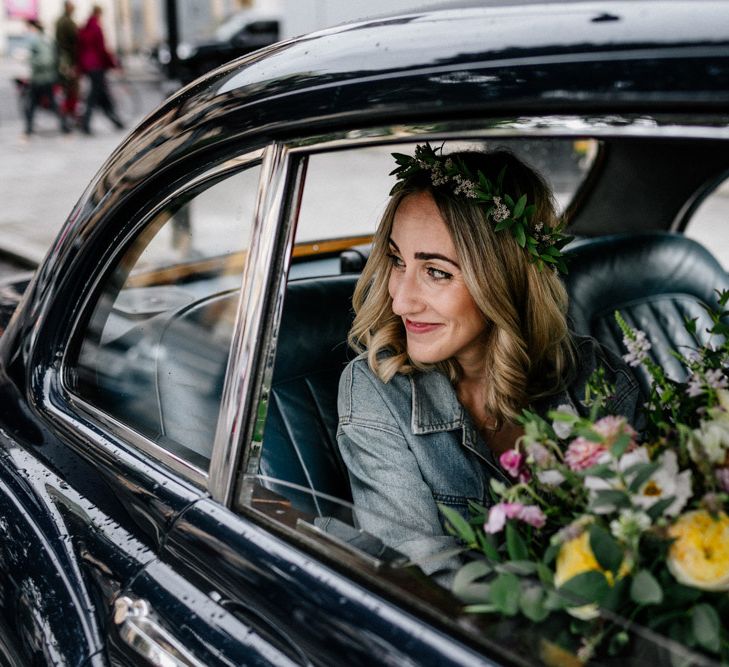 Bride in the wedding car holding her colourful wedding bouquet