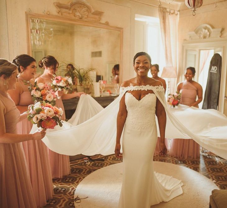 Bridesmaids helping the bride into her wedding cape