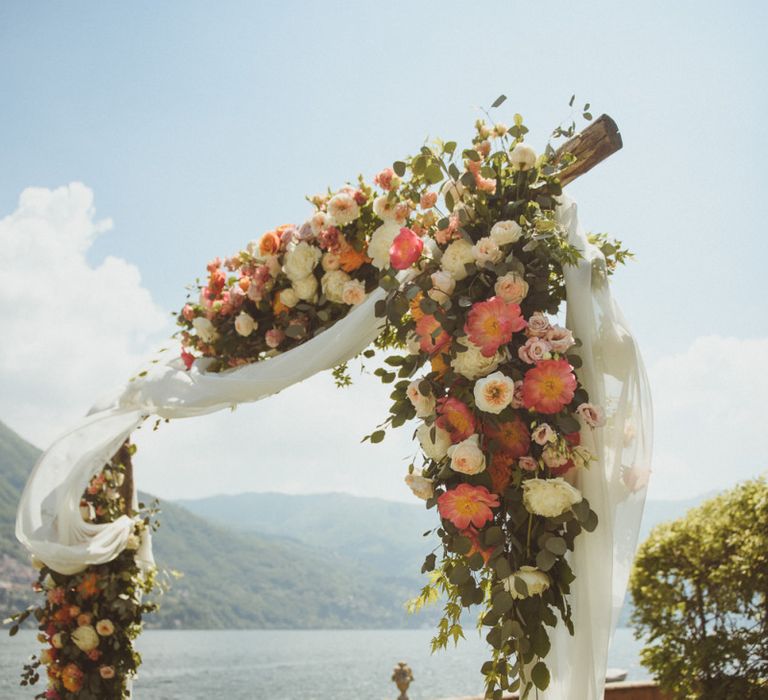 Wedding arch with, drapes and white and coral flowers