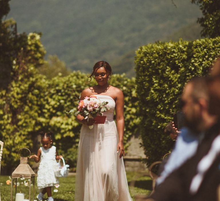 Bridesmaid in strapless dress walking down the aisle