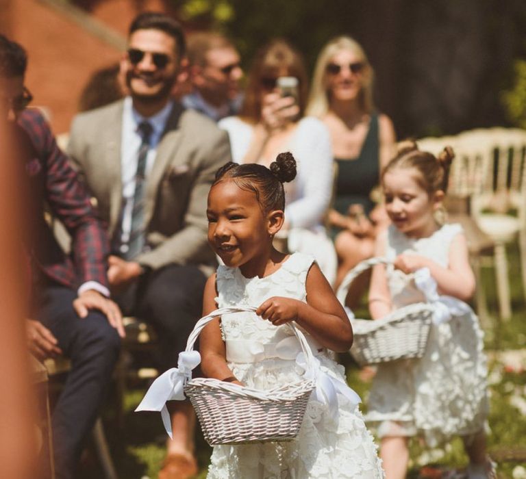 Flower girl in white dress with basket of petals