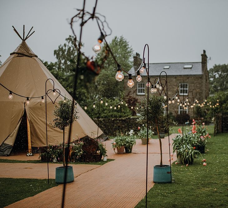 Festoon lIghts on Shepherds Crooks. Tipi Wedding at Home, Cumbria. Pale Dusky Pink, White and Mocha Flowers, Handwritten Details and Festoon Lights. Bride wears Essence of Australia Dress from Angelica Bridal. Groom wears Olive Next Suit and Tan Office Shoes.