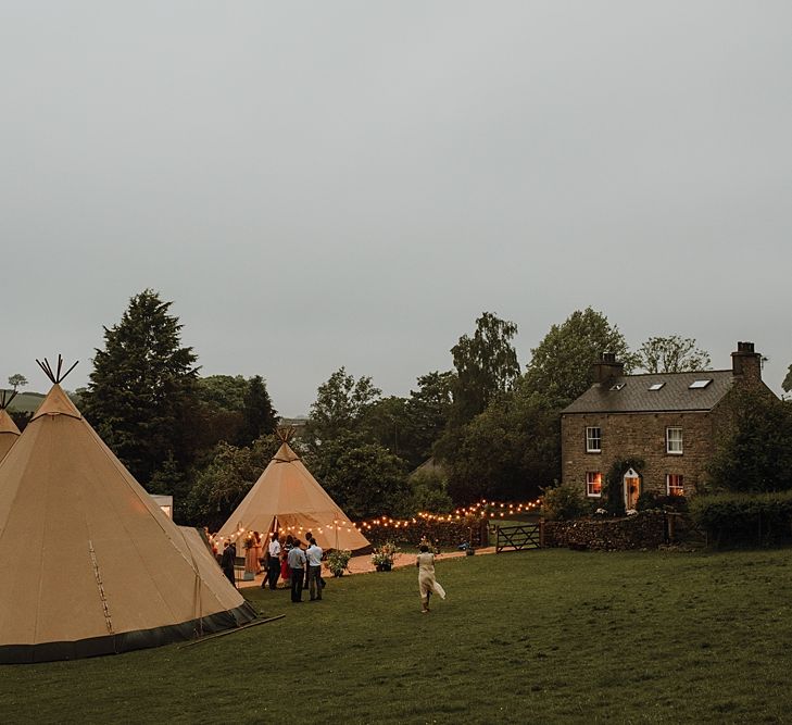 Tipi Wedding at Home, Cumbria. Pale Dusky Pink, White and Mocha Flowers, Handwritten Details and Festoon Lights. Bride wears Essence of Australia Dress from Angelica Bridal. Groom wears Olive Next Suit and Tan Office Shoes.