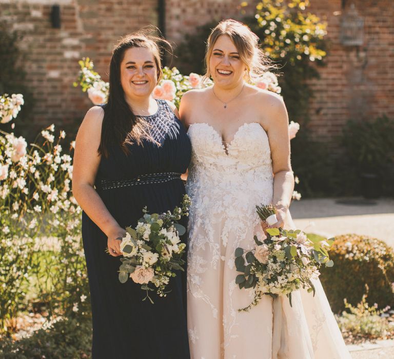 Bride in Pronovias wedding dress with bridesmaid in navy dress