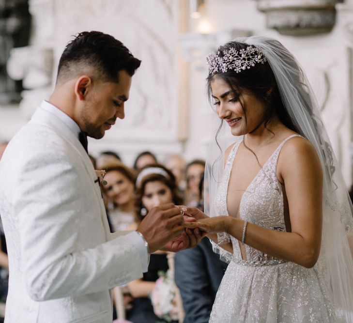 Bride and groom exchanging rings with bride in Berta Bridal gown