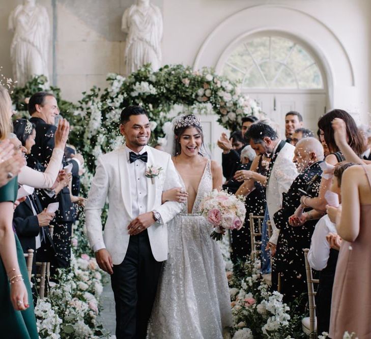 Bride in Berta Bridal wedding dress and Groom in white dinner jacket walking up the aisle as husband and wife