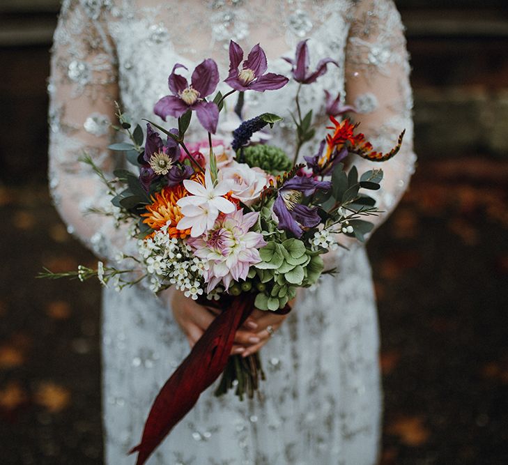 Purple, Orange and Pink Flowers with Foliage and Maroon Trailing Ribbon | Bride in Bead Embellished Needle &amp; Thread Gown with Cascading Tulle Skirt and Semi-Sheer Sleeves | Mariachi Band and Persian Rug Aisle for Autumn Wedding | Leah Lombardi Weddings