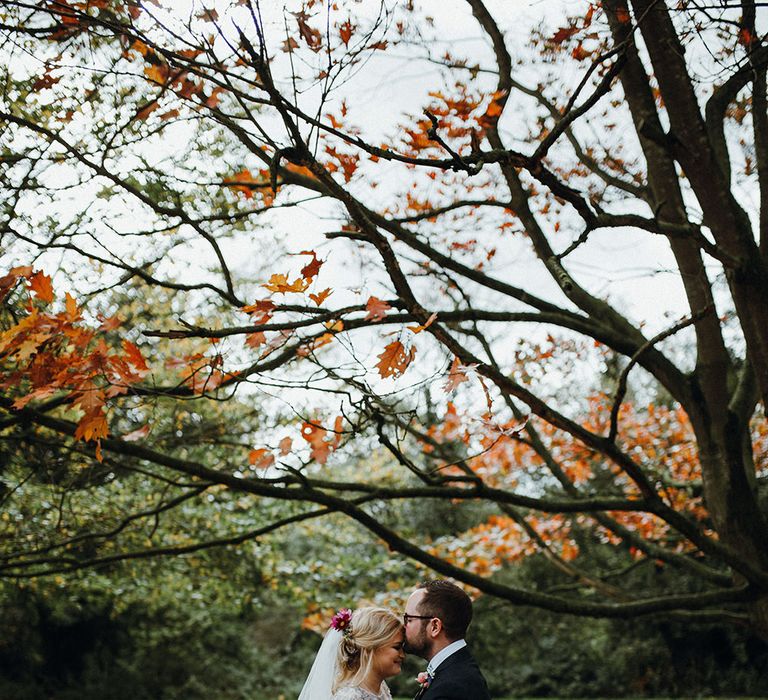 Bride in Bead Embellished Needle &amp; Thread Gown with Cascading Tulle Skirt and Semi-Sheer Sleeves | Elbow Length Veil | Bridal Up Do with Pink Hair Flowers | Groom in Check Blue Three-Piece Suit by T.M.Lewin with Maroon Tie and Pocket Square | Purple, Orange and Pink Flowers with Foliage and Maroon Trailing Ribbon | Mariachi Band and Persian Rug Aisle for Autumn Wedding | Leah Lombardi Weddings