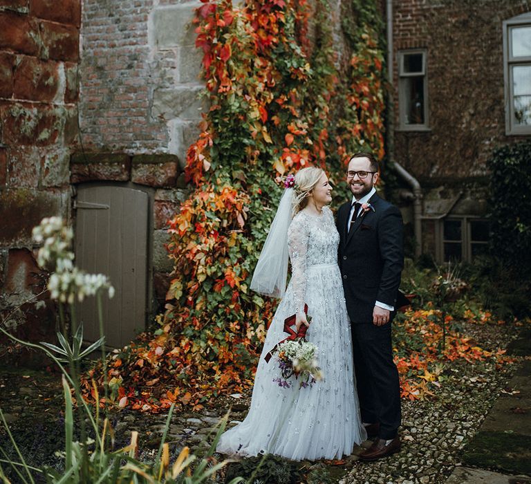 Bride in Bead Embellished Needle &amp; Thread Gown with Cascading Tulle Skirt and Semi-Sheer Sleeves | Elbow Length Veil | Bridal Up Do with Pink Hair Flowers | Groom in Check Blue Three-Piece Suit by T.M.Lewin with Maroon Tie and Pocket Square | Purple, Orange and Pink Flowers with Foliage and Maroon Trailing Ribbon | Mariachi Band and Persian Rug Aisle for Autumn Wedding | Leah Lombardi Weddings