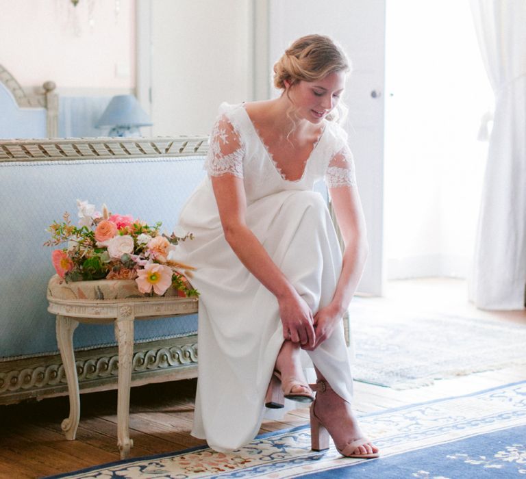 Bride putting on Shoes in a Lace Cap Sleeve Wedding Dress From Croque Lune