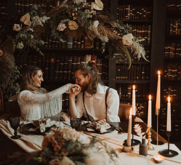 Groom with Top Knot Kissing His Brides Hand in a Fringe Sleeve Bridal Separates