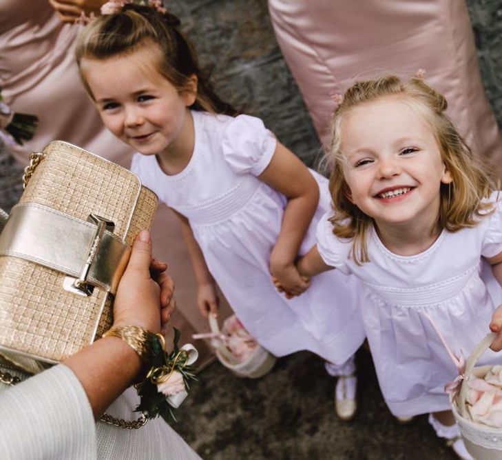 Flower girls wearing white dresses and petal confetti baskets at Wales wedding venue