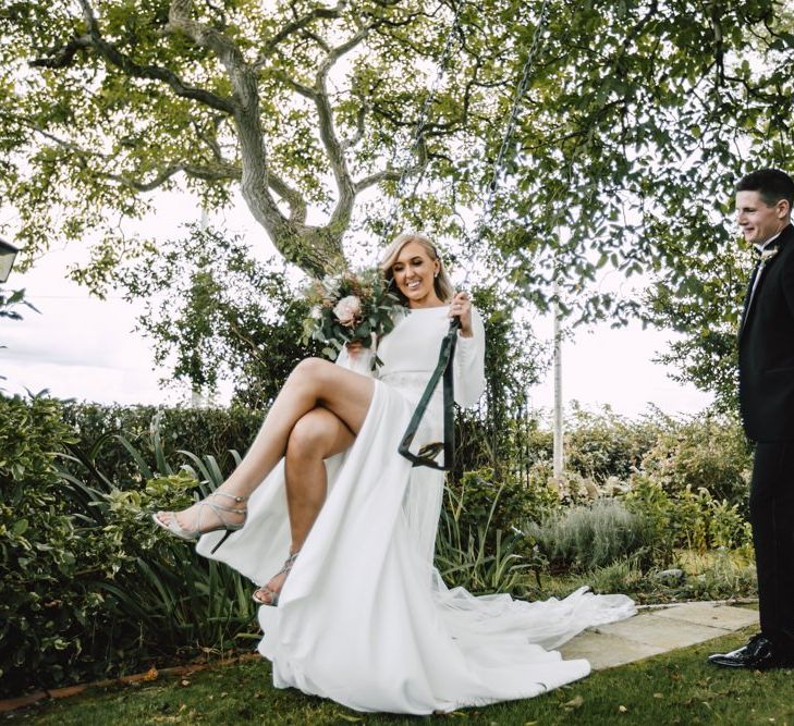 Bride and groom at Wales wedding venue wearing split front dress and lace tipped long veil