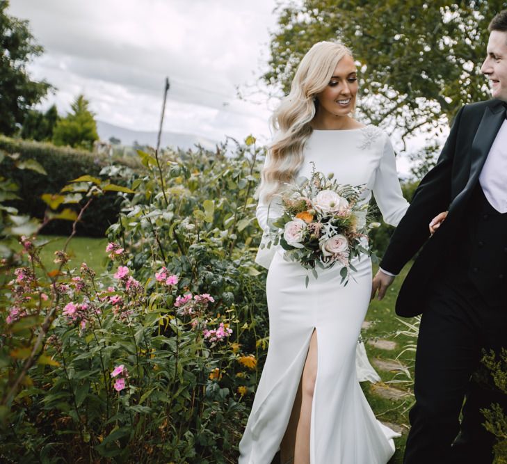 Bride and groom at autumn celebration wearing split front dress with lace tipped long veil and groom in black tie