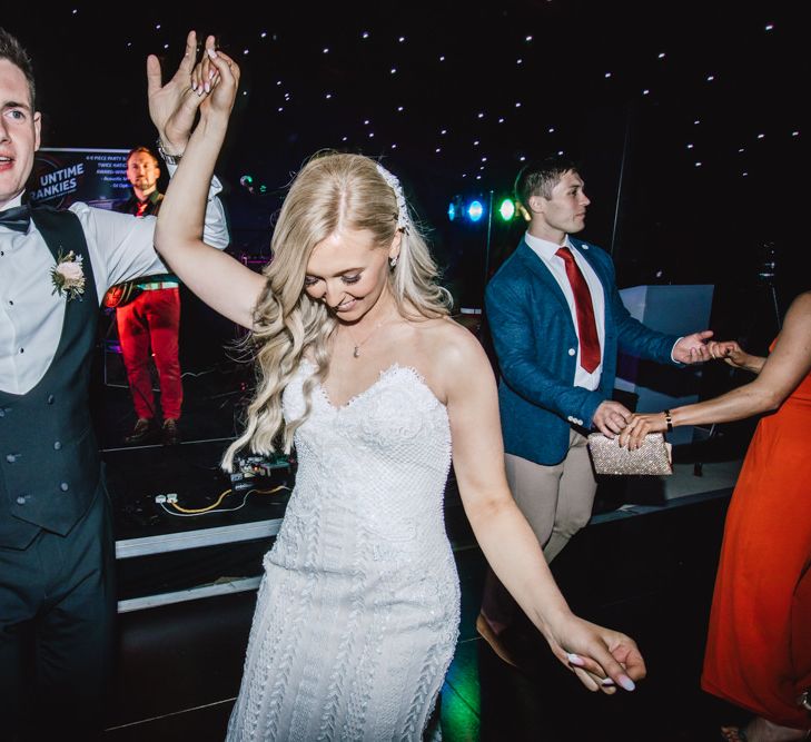 Bride and groom celebrate at their marquee reception wearing strapless evening gown