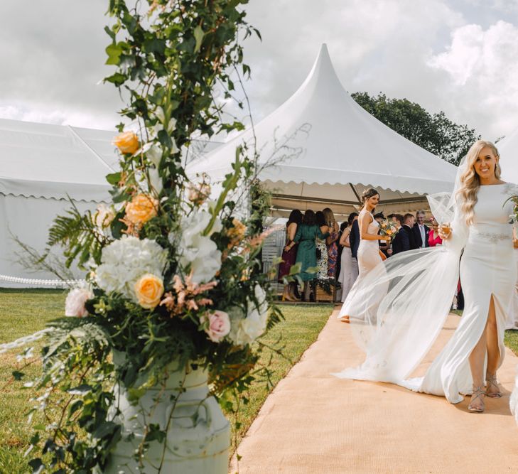 Bride wearing a classic split front wedding dress and long lace tipped veil at marquee reception with dog