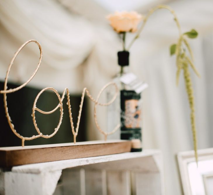 Gold 'love' sign with peach rose floral decor at marquee reception with equestrian details