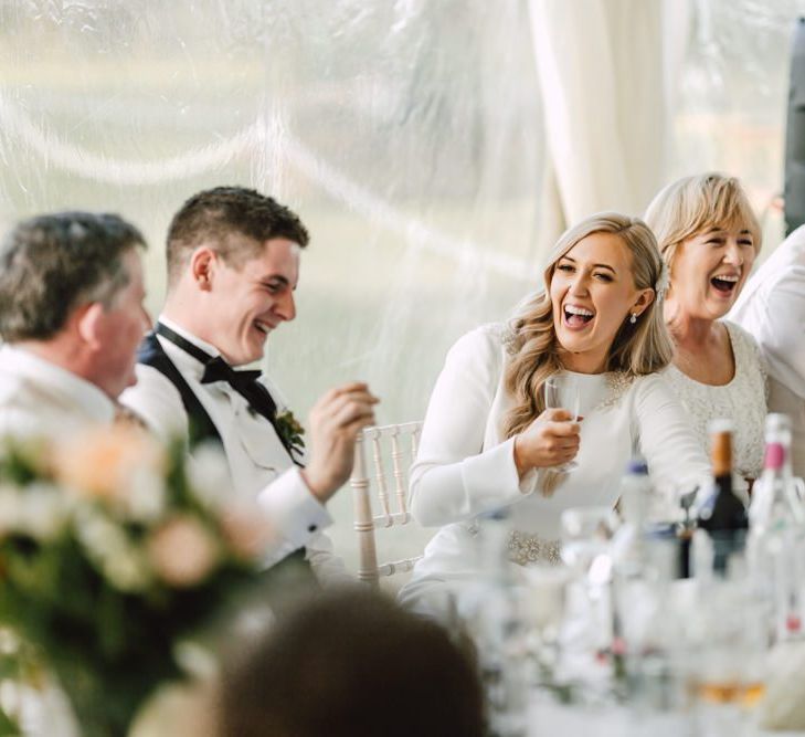 Bride and groom celebrate at their marquee reception with peachy pink rose floral decor