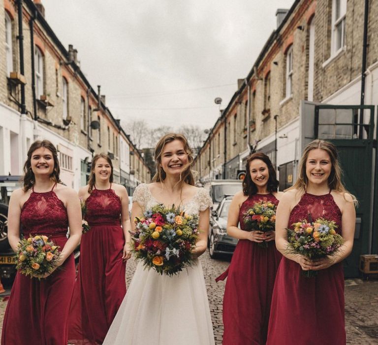 Bridal party portrait with bridesmaids in red dress holding colourful bouquets