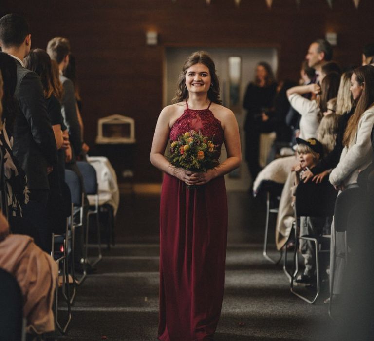 Bridesmaid in red dress walking down the aisle