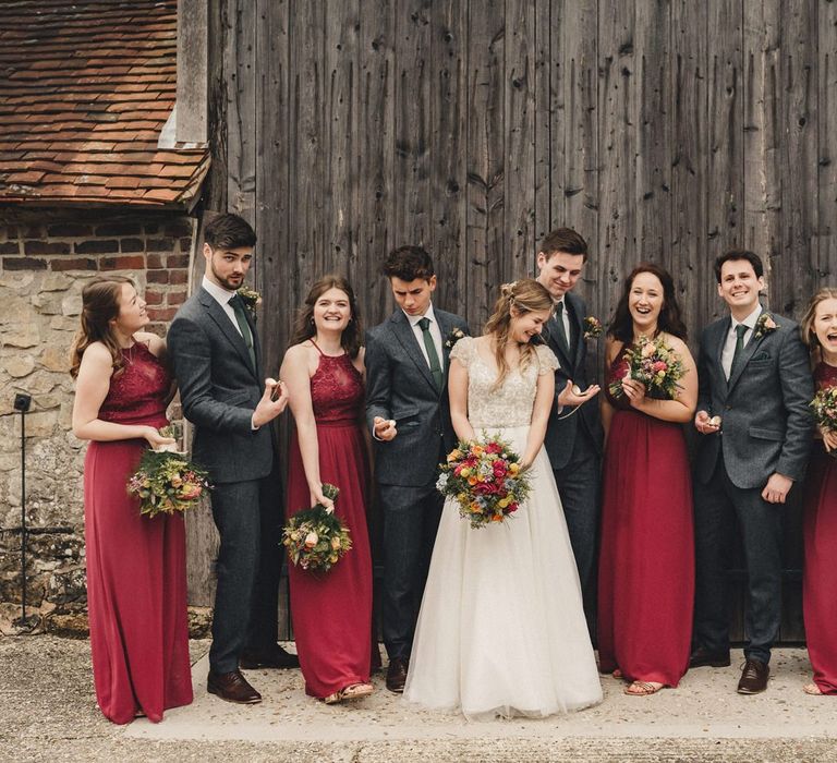 wedding party portrait with bridesmaids in red dresses and groomsmen in dark blue wool suits