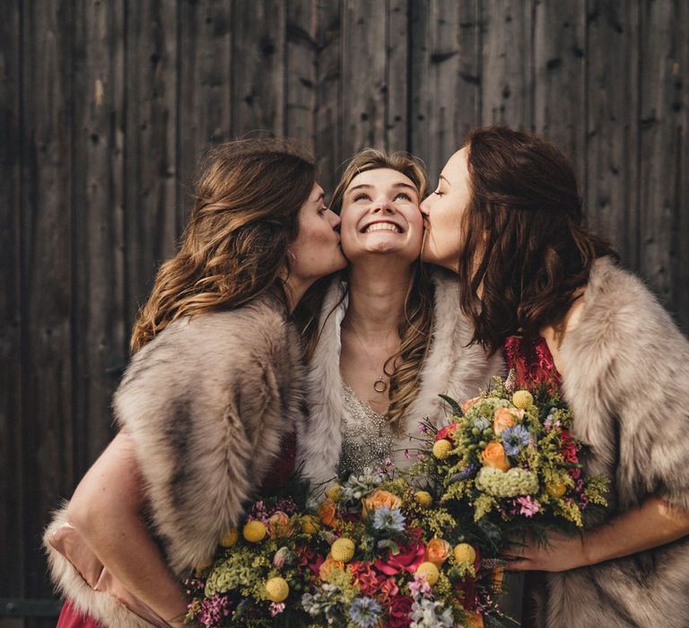 bride with her bridesmaids kissing her cheeks