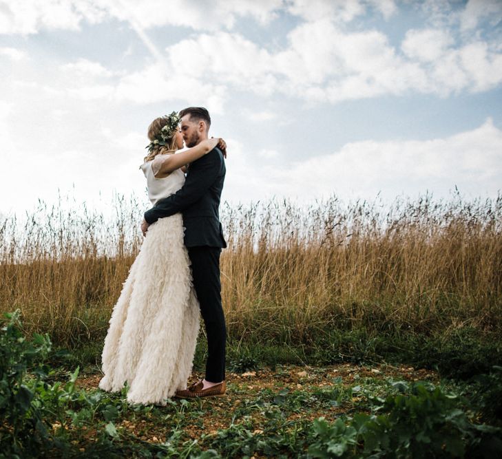 Bride in Halfpenny London Swan Tulle Petal Skirt and Flower Crown and Groom in Wool Suit &amp; Bow Tie Embracing