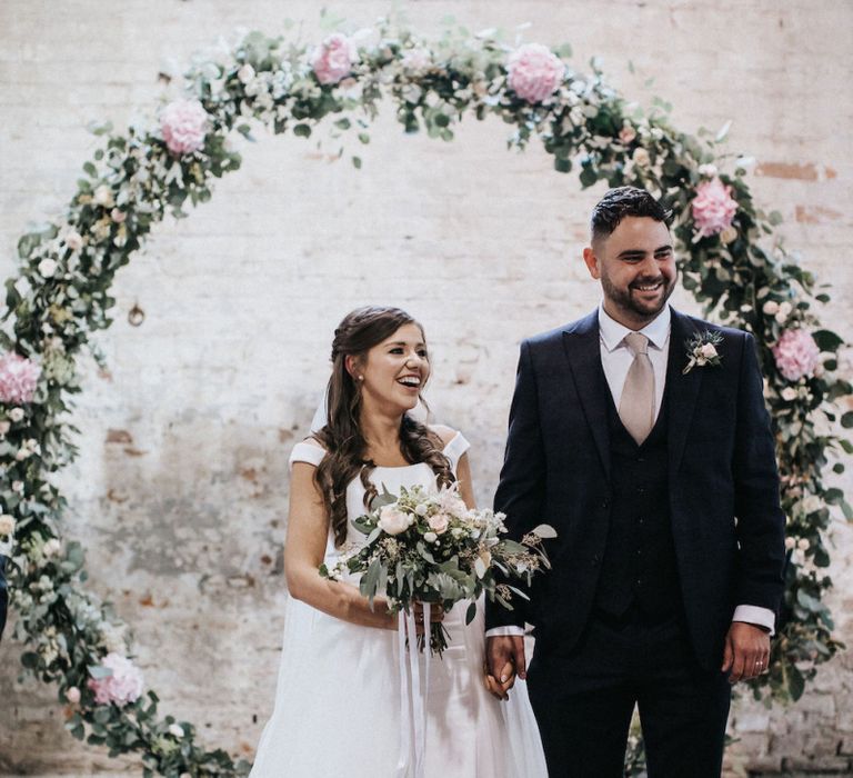 Bride and Groom Standing in Front of a Floral Moon Gate