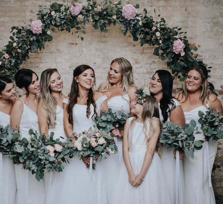 Bridal Party in White Standing in Front of a Floral Moon Gate