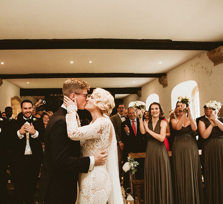 Bride in Vintage Style Tara Lauren Wedding Dress  and Groom in Black Tie Kissing During Wedding Ceremony