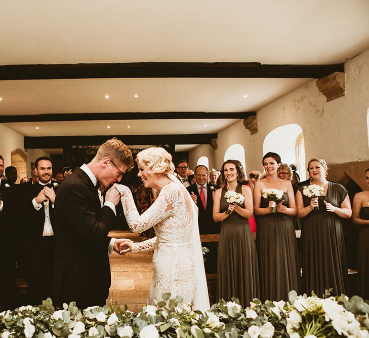 Bride in Vintage Style Tara Lauren Wedding Dress  and Groom in Black Tie Holding Hands During Wedding Ceremony