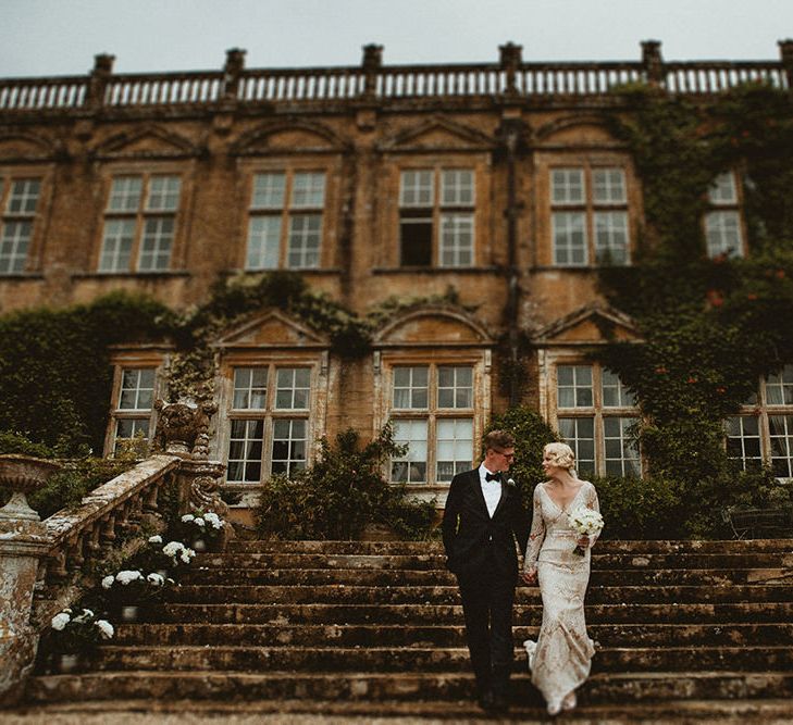 Bride in Vintage Lace Tara Lauren Wedding Dress and Groom in Black Tie Suit Standing Front of Brympton House Wedding Venue