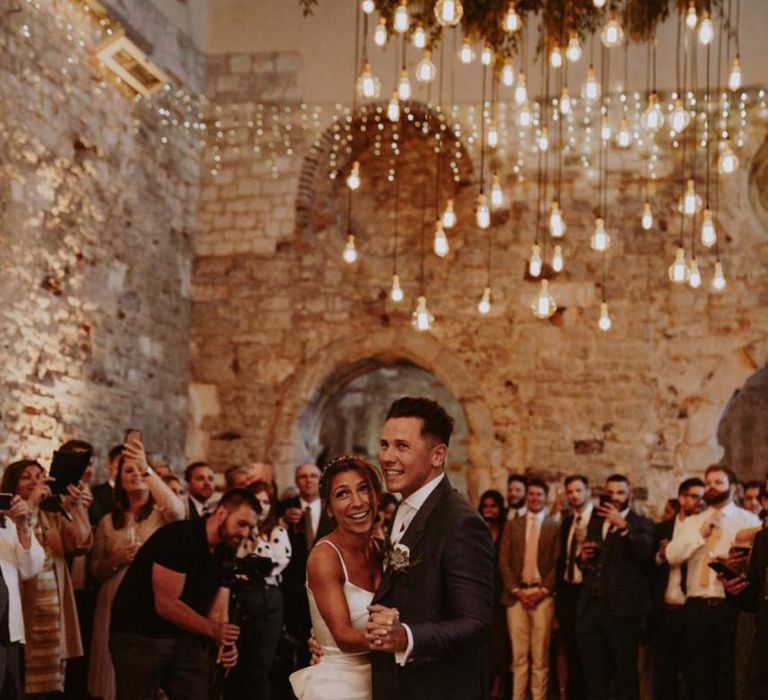 Bride and groom first dance under hanging light installation