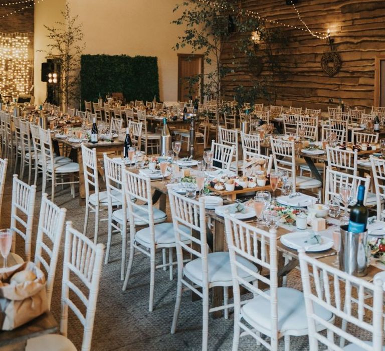 Wedding breakfast decor with foliage chandelier and fairy light backdrop