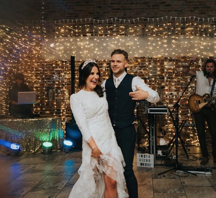 Bride and groom dance in front of fairy light backdrop