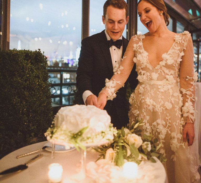 Bride in Marchesa dress with groom cutting the wedding cake