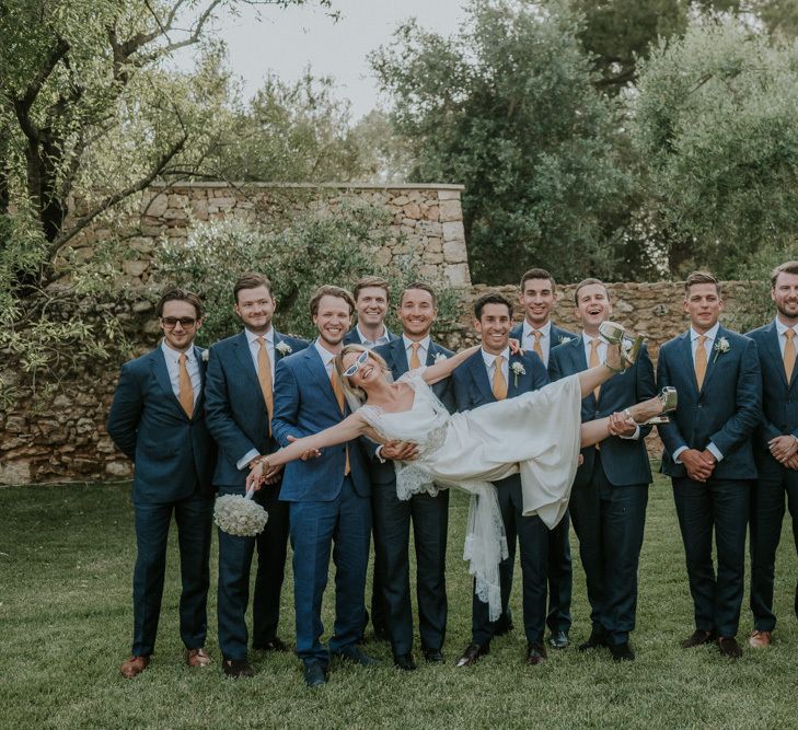 Groomsmen in Navy Blue Suits Holding Up Bride in Halfpenny Wedding Dress