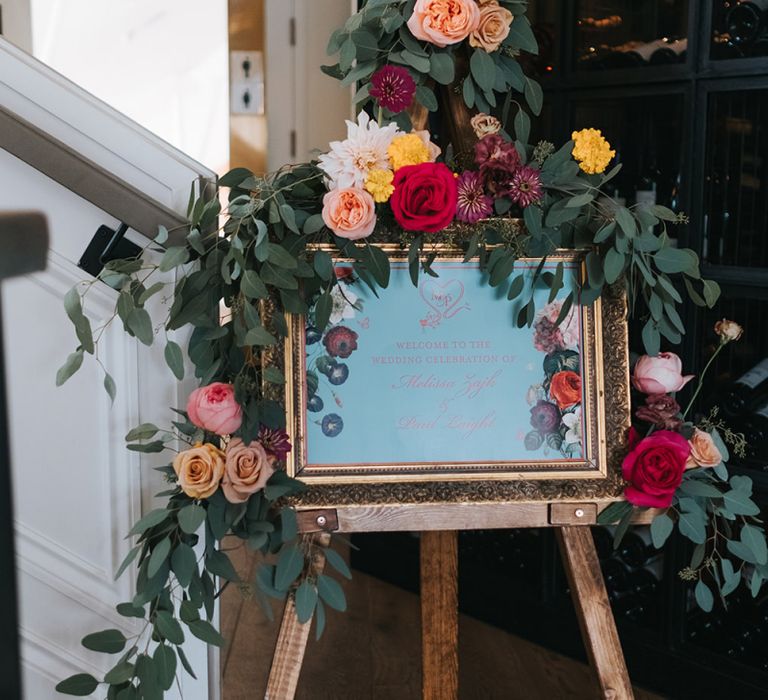 Wedding Welcome Sign in Gold Frame | Wooden Easel | Eucalyptus Garland with Colourful Flowers | Meringue Kisses &amp; Colourful Wedding Flowers &amp; Stationery for a London Wedding at The Globe | Miss Gen