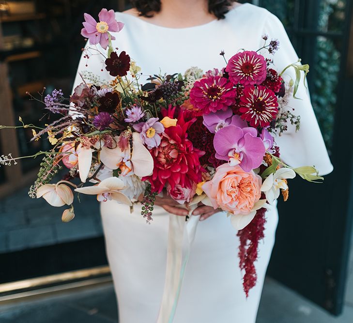 Colourful Deconstructed Bridal Bouquet of Red and Pink Flowers with Trailing Ribbon | Bride in Halfpenny London Dress with Cowl Back and Half Length Sleeves | Meringue Kisses &amp; Colourful Wedding Flowers &amp; Stationery for a London Wedding at The Globe | Miss Gen