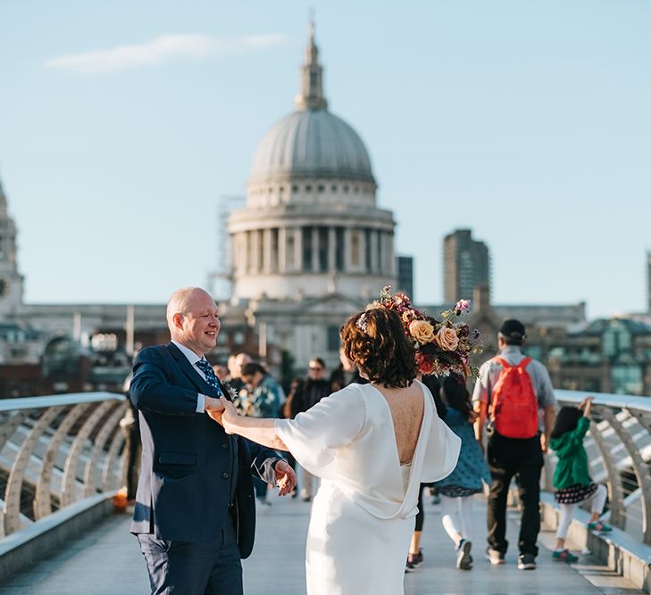 Bride in Halfpenny London Dress with Cowl Back and Half Length Sleeves | Colourful Deconstructed Bridal Bouquet of Red and Pink Flowers with Trailing Ribbon | Tilly Thomas Lux Headband | Groom in Blue Three-Piece Suit and White Trainers | Wedding Photo at St Paul's Cathedral | Meringue Kisses &amp; Colourful Wedding Flowers &amp; Stationery for a London Wedding at The Globe | Miss Gen