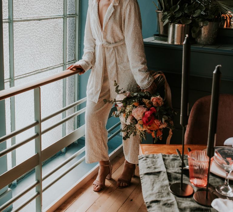 Stylish Bride in Wrap Sequin Jump-suit Standing by a Retro Tablescape