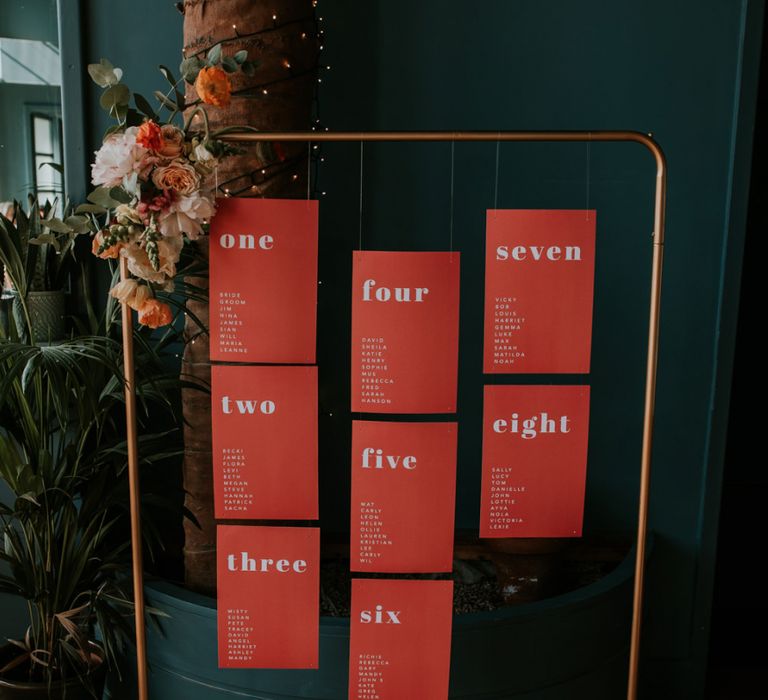 Copper Frame Table Plan with Statement Table Stationery Hanging From it Decorated with Flowers