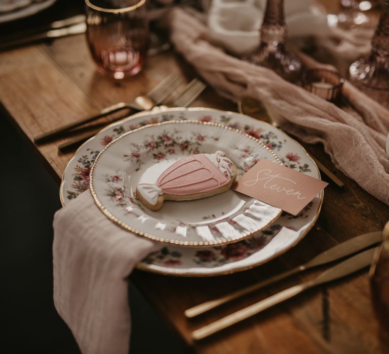 Place setting with patterned china, cookie wedding favour and blush pink wedding stationery