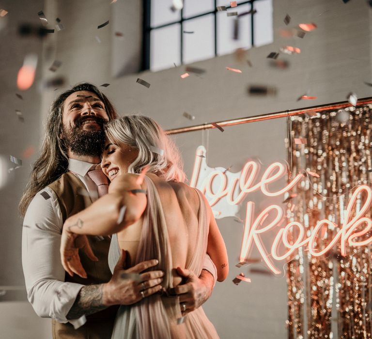 Metallic confetti moment with blush pink neon sign in the background