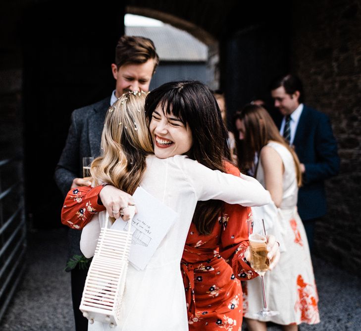 Stylish Wedding Guest in Red Floral Dress and Bangs Hugging The Bride